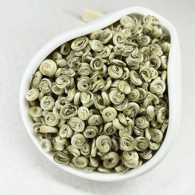 Loose jasmine green tea pearls in a white ceramic dish
